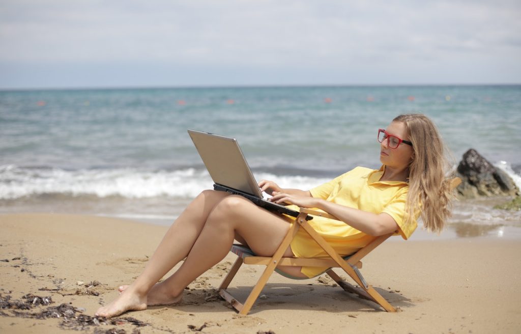 A woman working on her laptop while on the beach