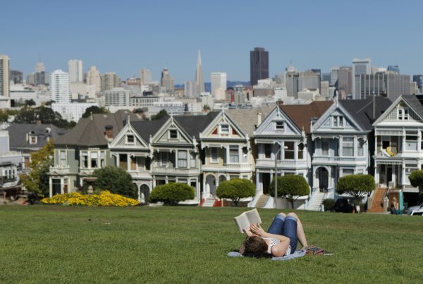 a woman lying in the grass, reading a book- finding work-life balance in San Francisco