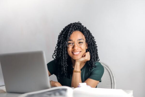 A girl sitting behind a laptop and smiling